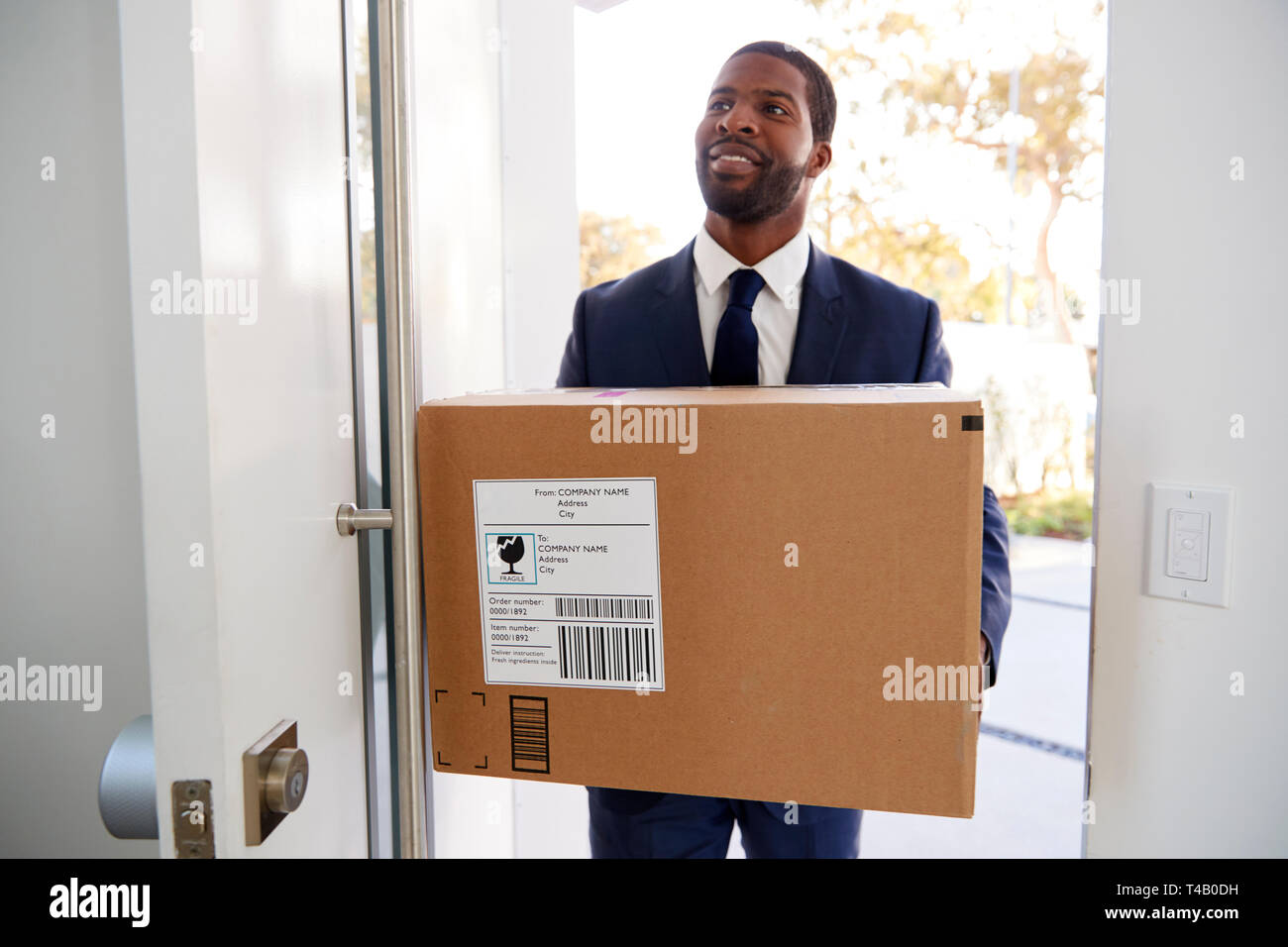 Businessman Carrying Box Opening Door Returning Home From Work Stock Photo