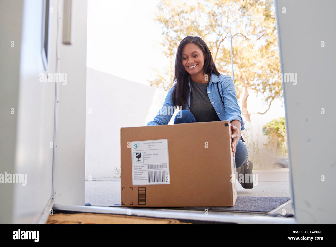 Woman Coming Back To Home Delivery In Cardboard Box Outside Front Door Stock Photo