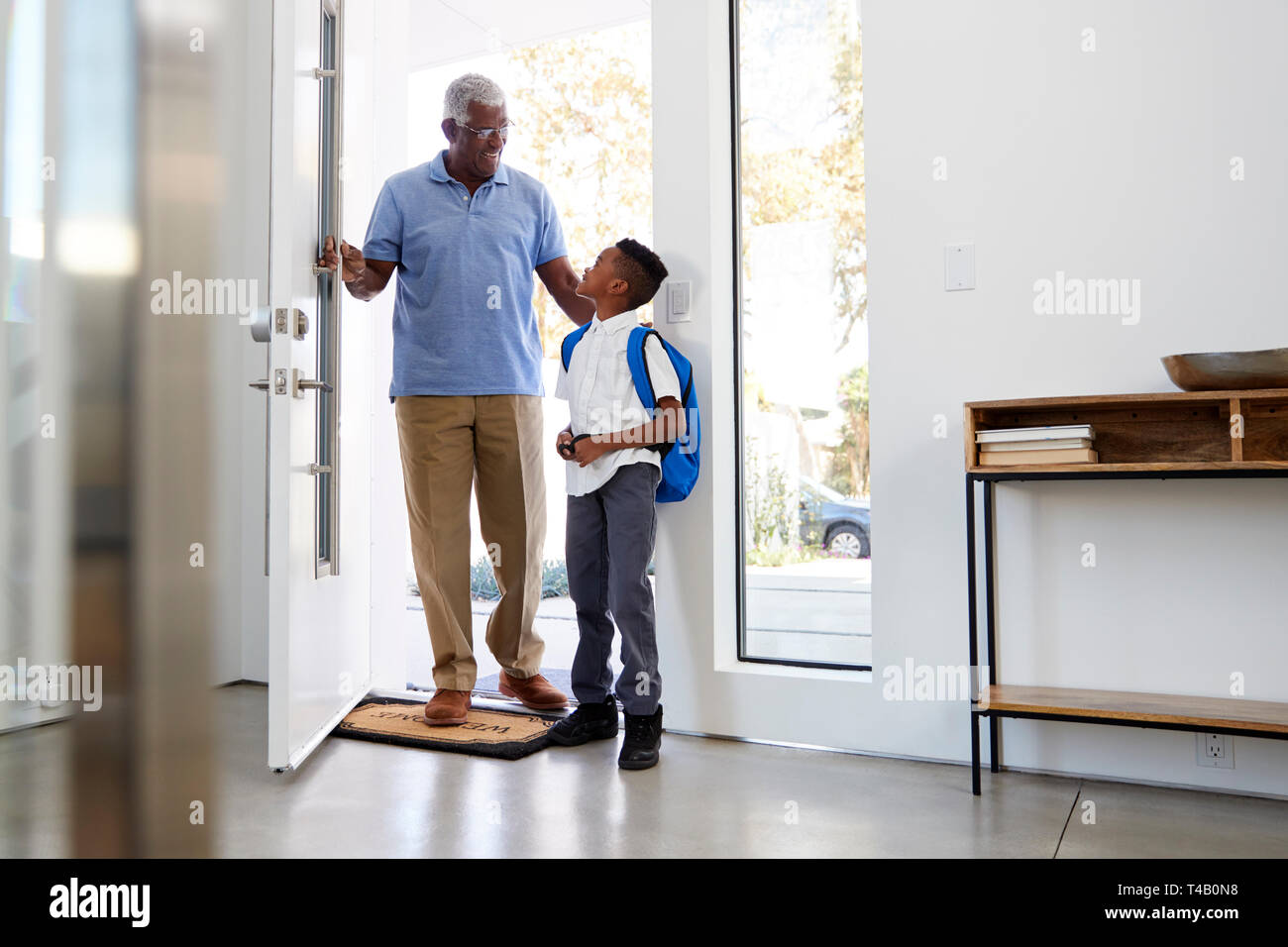 Grandfather Collecting And Bringing Grandson Home After School Stock Photo