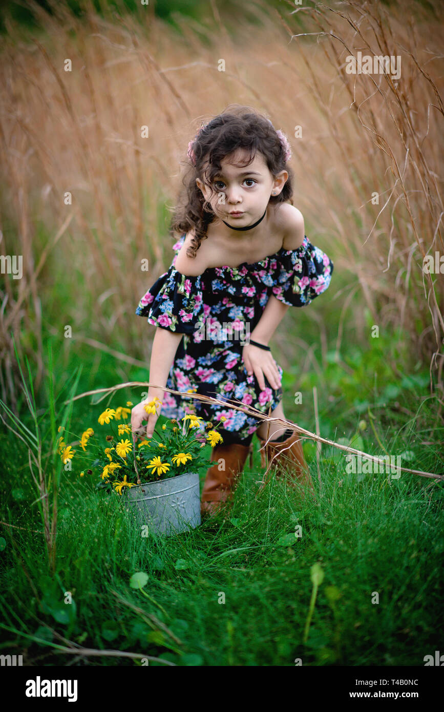 Young girl in hat and boots in tall grass field Stock Photo