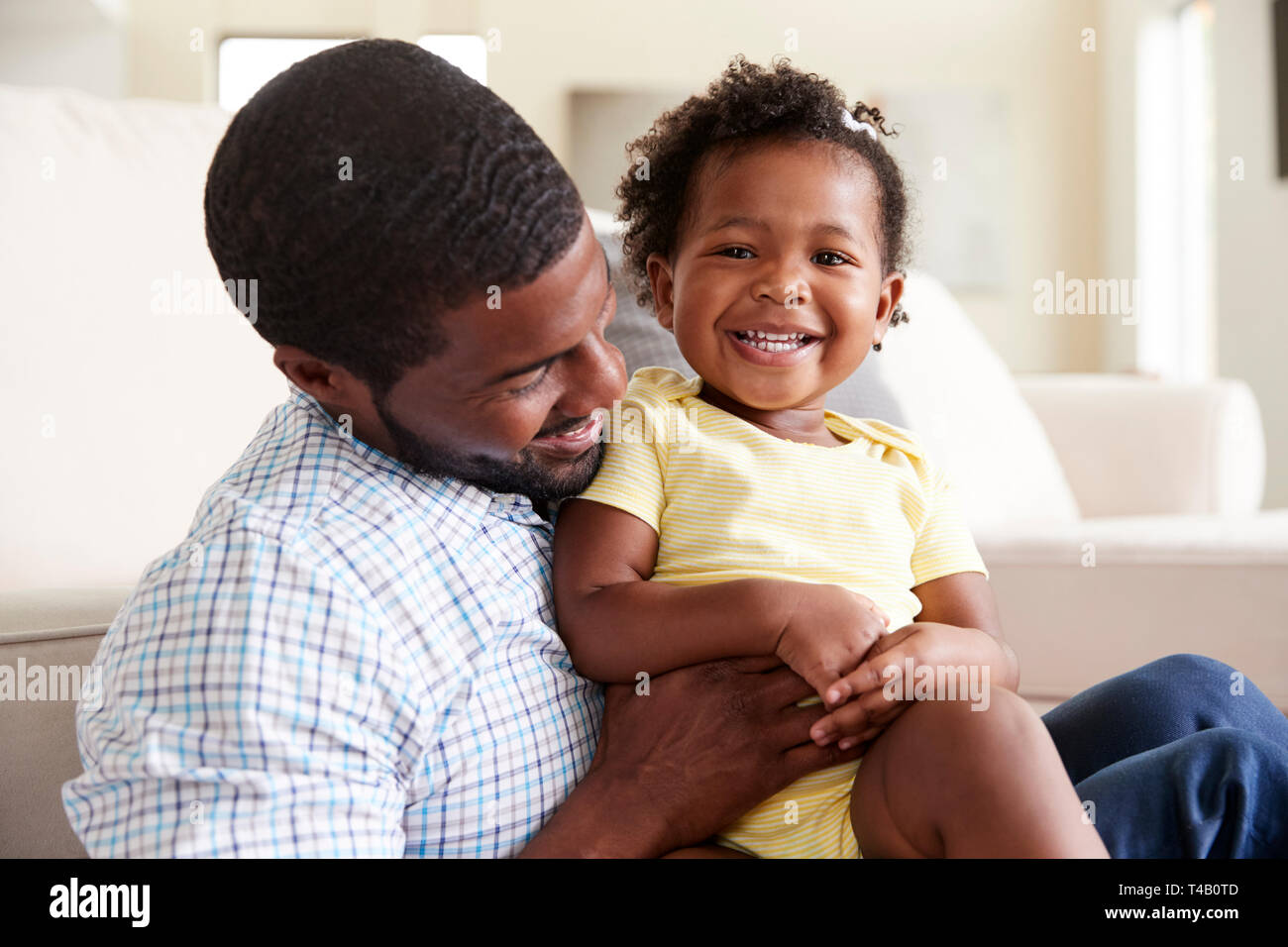 Baby Daughter Playing With Father On Sofa In Lounge At Home Stock Photo