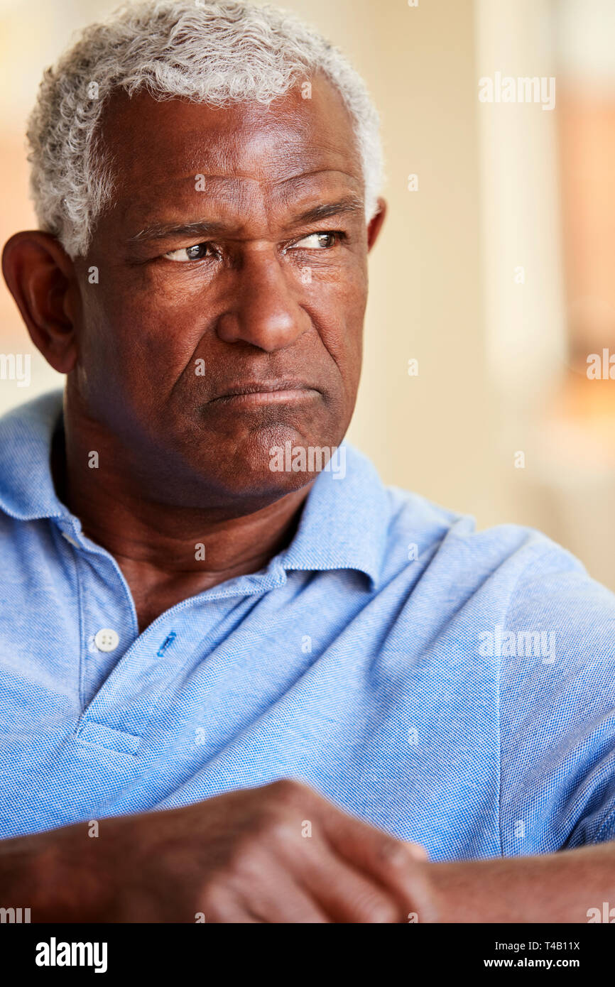 Thoughtful Senior Man Sitting On Sofa At Home Stock Photo