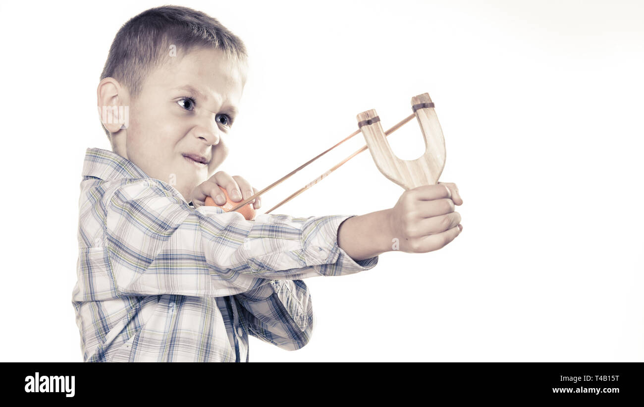 Children upbringing problems. Kid holding slingshot in hands. Bad