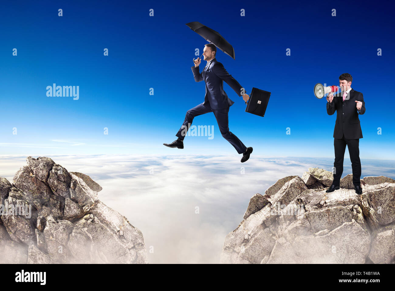 Businessman jumping over a cliff and collegue is cheering with bullhorn. Stock Photo