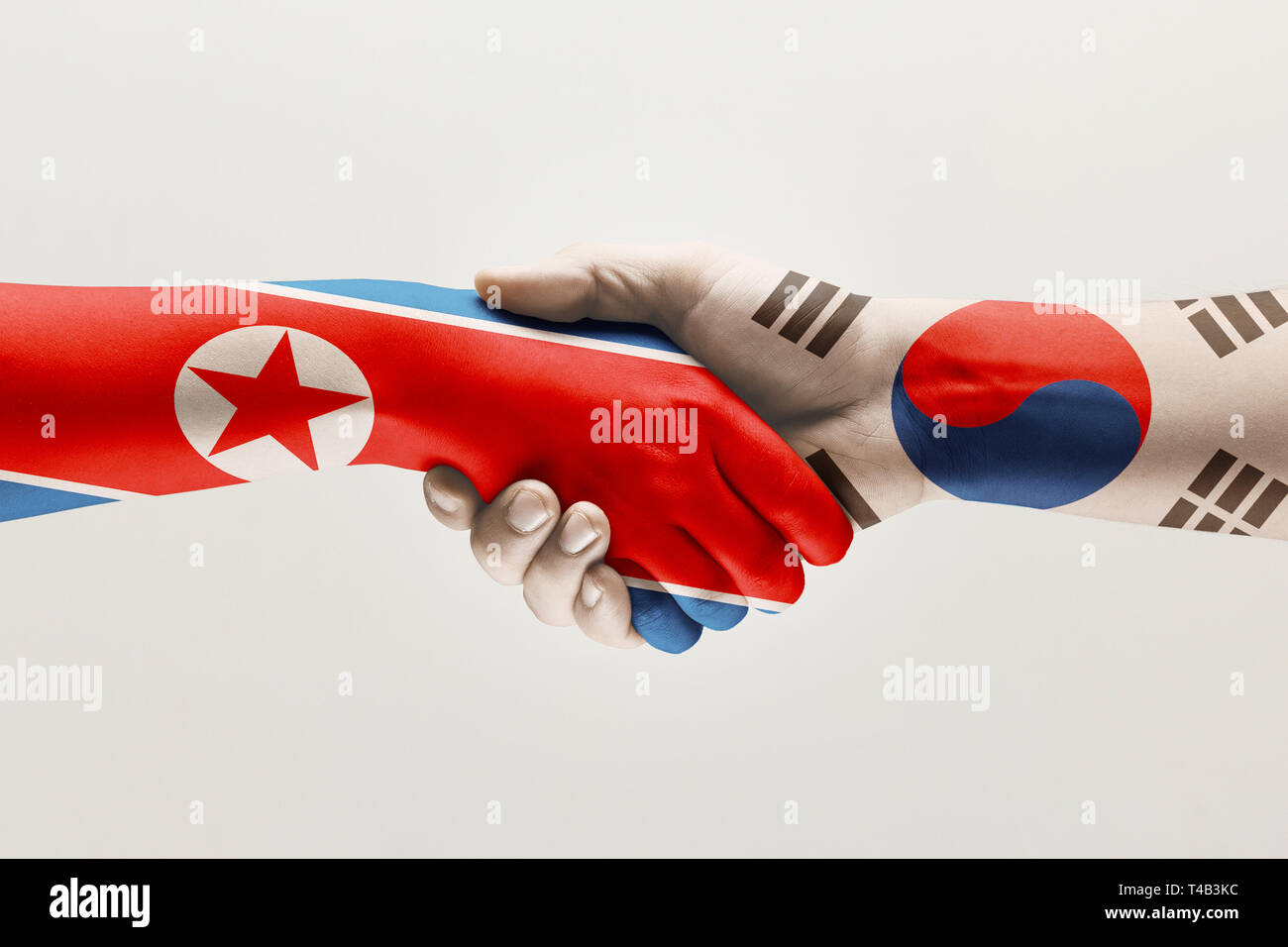 Let's try again. Two male hands shaking colored in flag of North and South Korea isolated on white studio background. Concept of help, partnership of countries, political and economical relations. Stock Photo