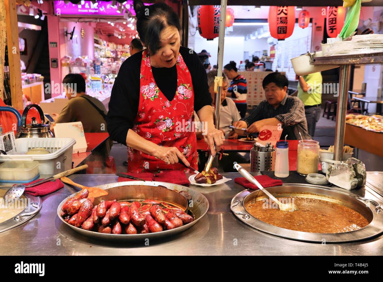 TAIPEI, TAIWAN - DECEMBER 4, 2018: Vendor sells deep fried sweet potatoes at Raohe Night Market in Taipei. Night food markets are a big part of Taiwan Stock Photo