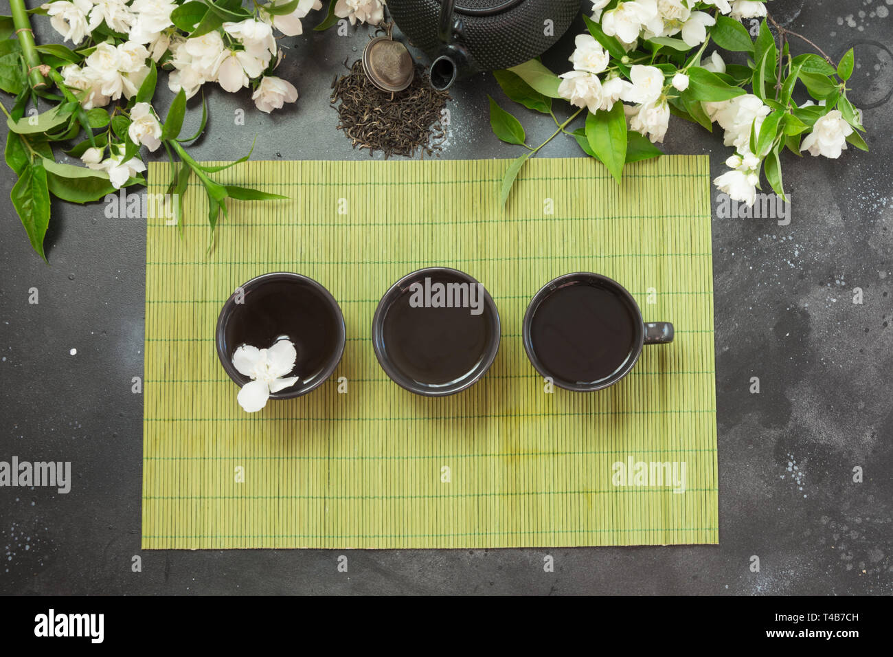 Green jasmin tea and jasmine flowers, cup of green tea on vintage grey
