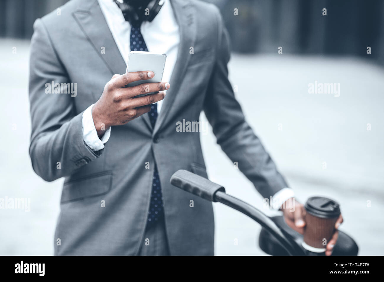 Businessman texting on phone leaning on the handlebars Stock Photo
