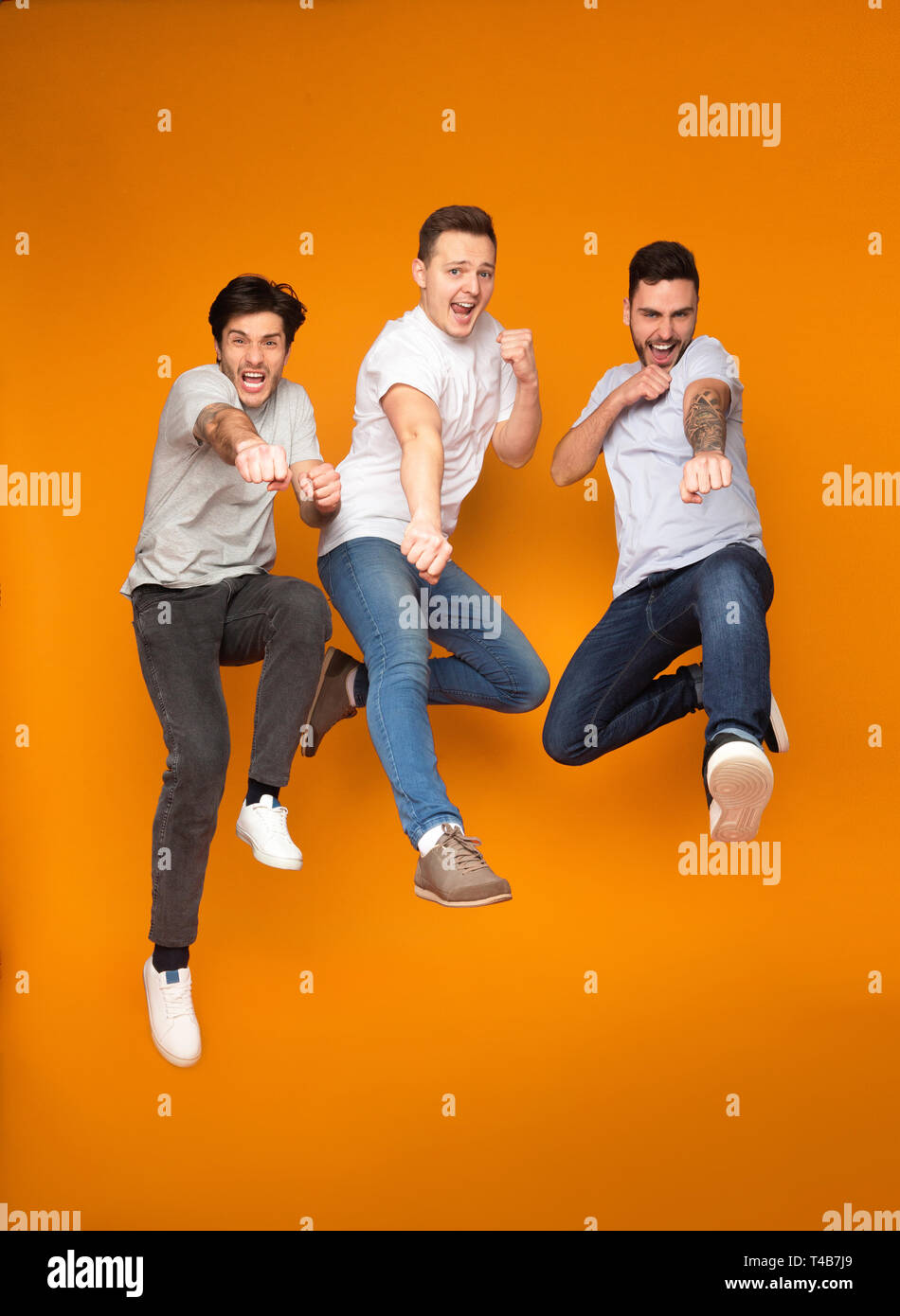 Three excited men jumping together, having fun Stock Photo