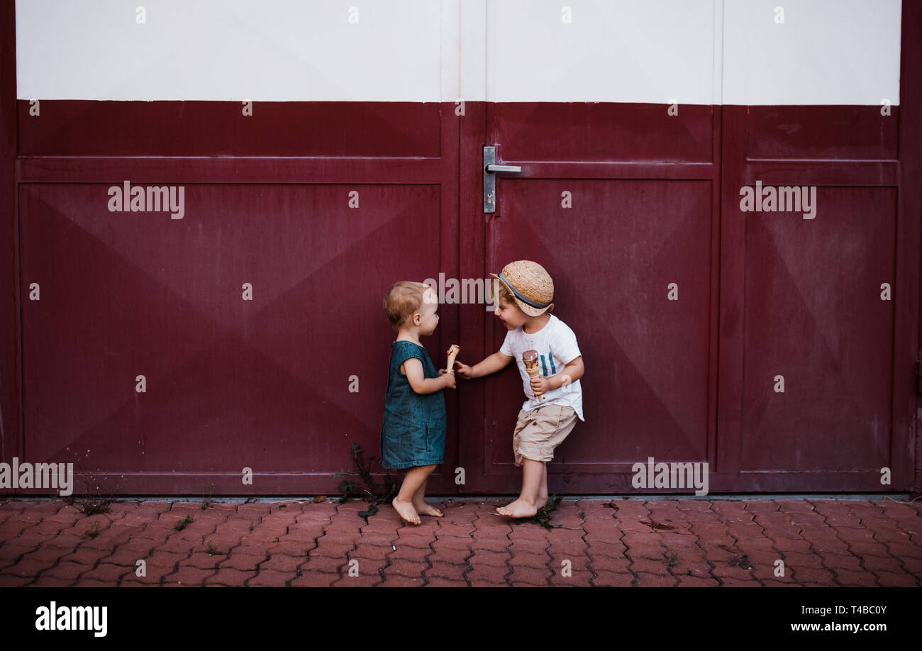 Small two toddler children outdoors in summer, eating ice cream. Stock Photo