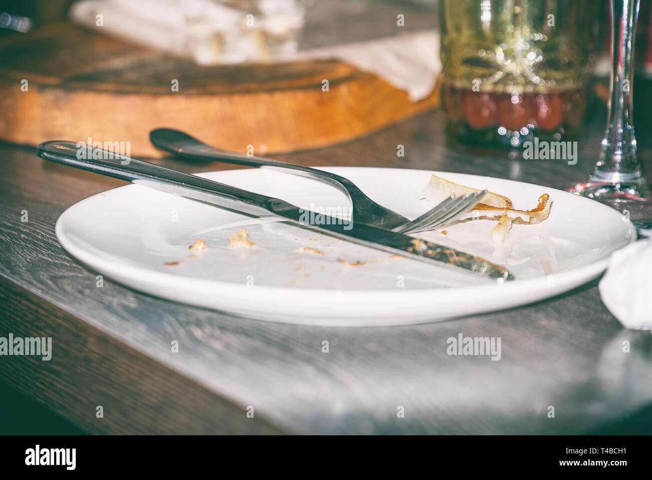 Knife and fork on dirty plate Stock Photo