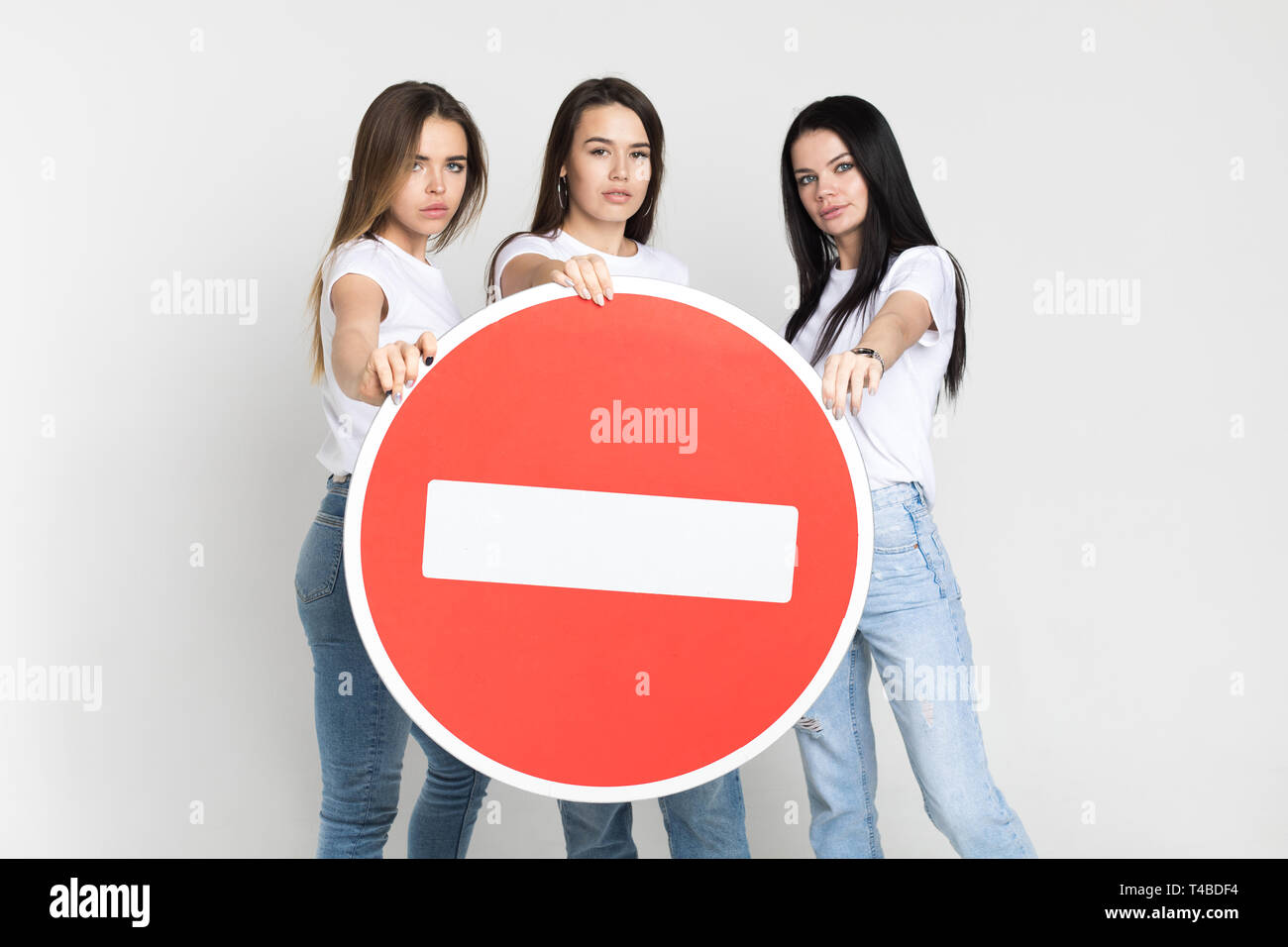 Three beautiful young women hold a big red sign Stock Photo - Alamy