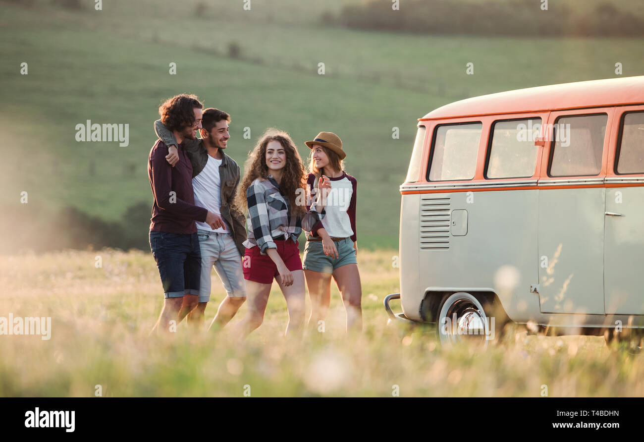 A group of young friends on a roadtrip through countryside, walking ...