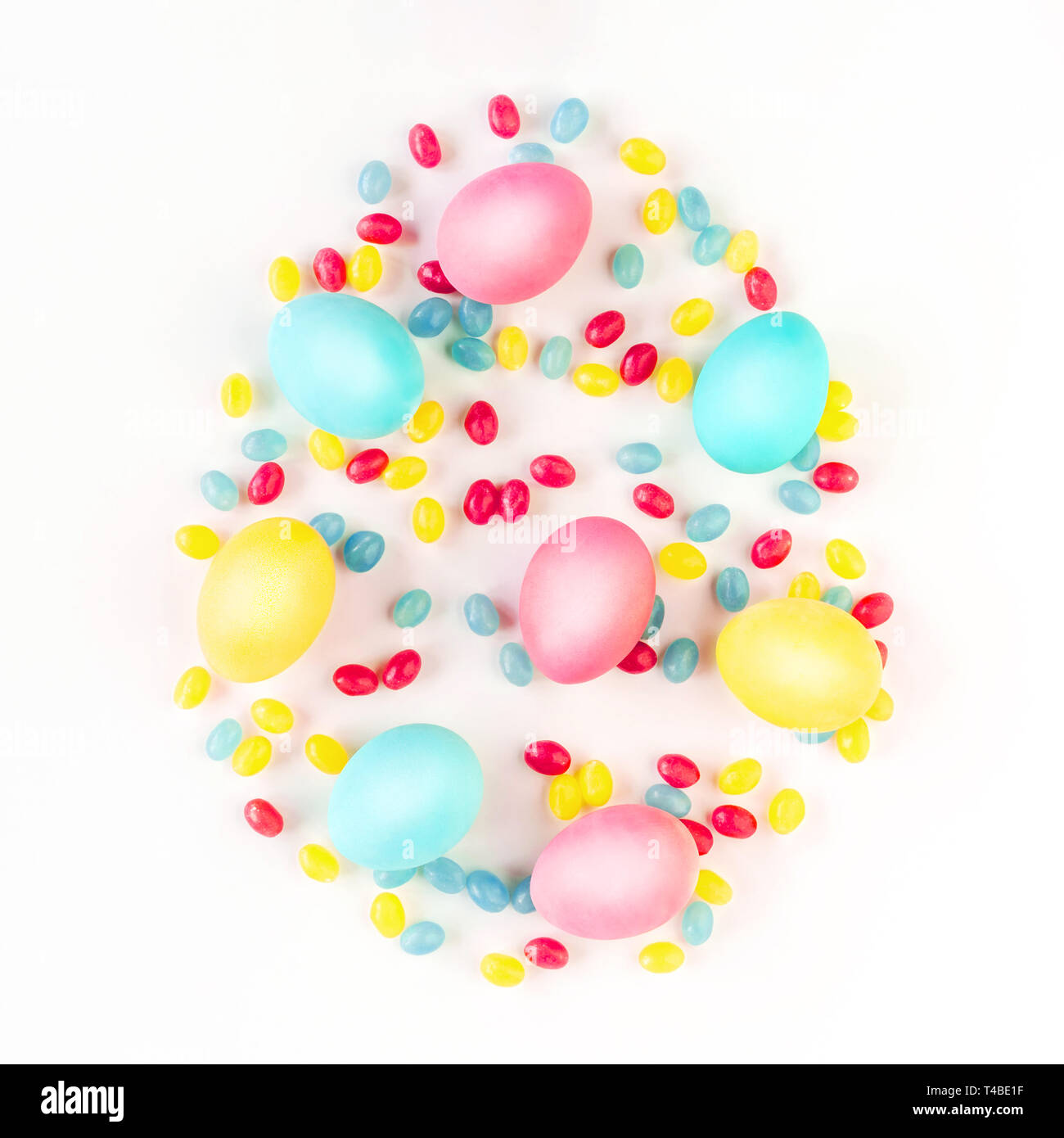 Easter egg concept. Colorful eggs and candies on isolated white background. Flat lay. Stock Photo