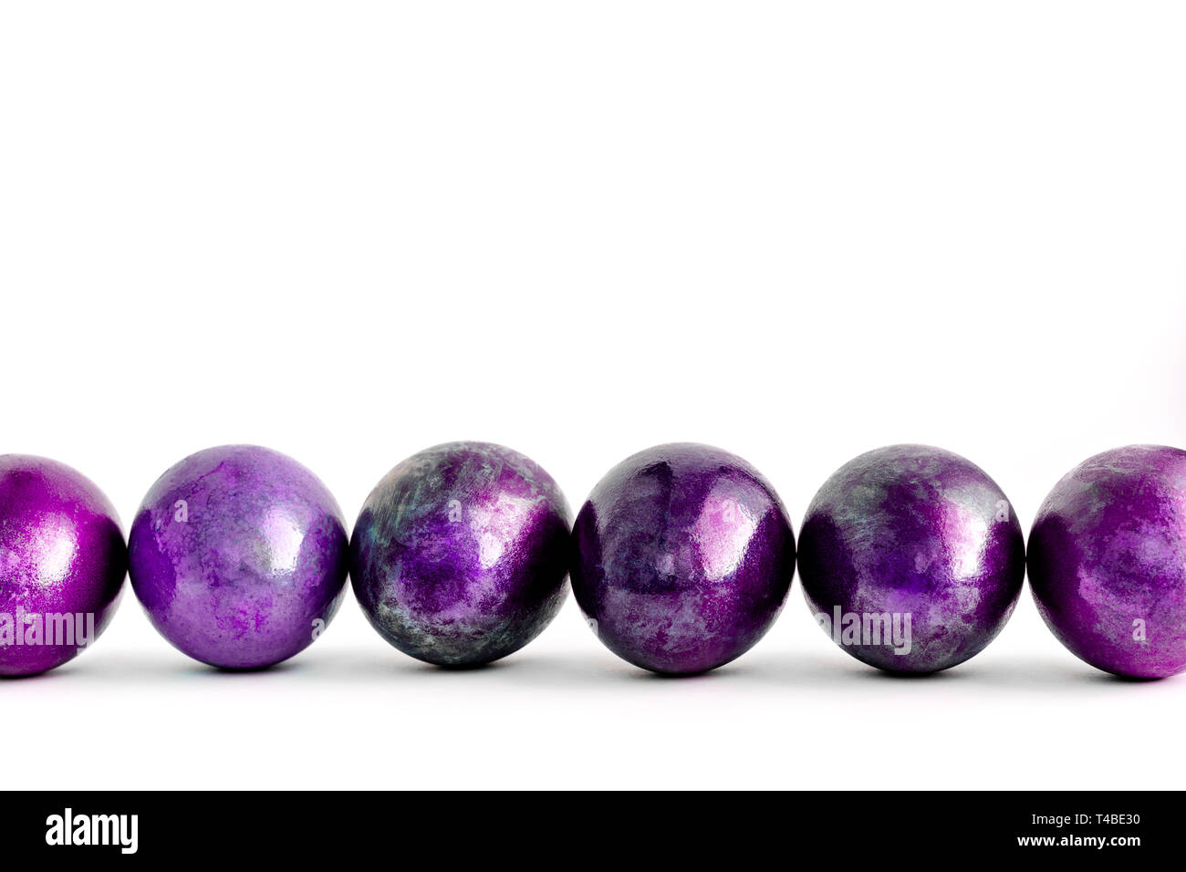 Easter eggs decorated in different shades of violet lined on isolated white background. Close-up. Stock Photo