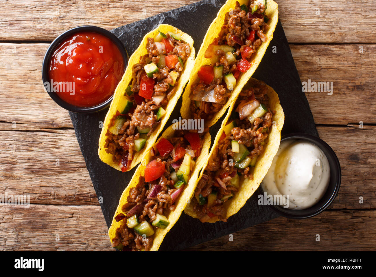 Mexican tacos stuffed with minced beef and vegetables close-up on the table. horizontal top view from above Stock Photo