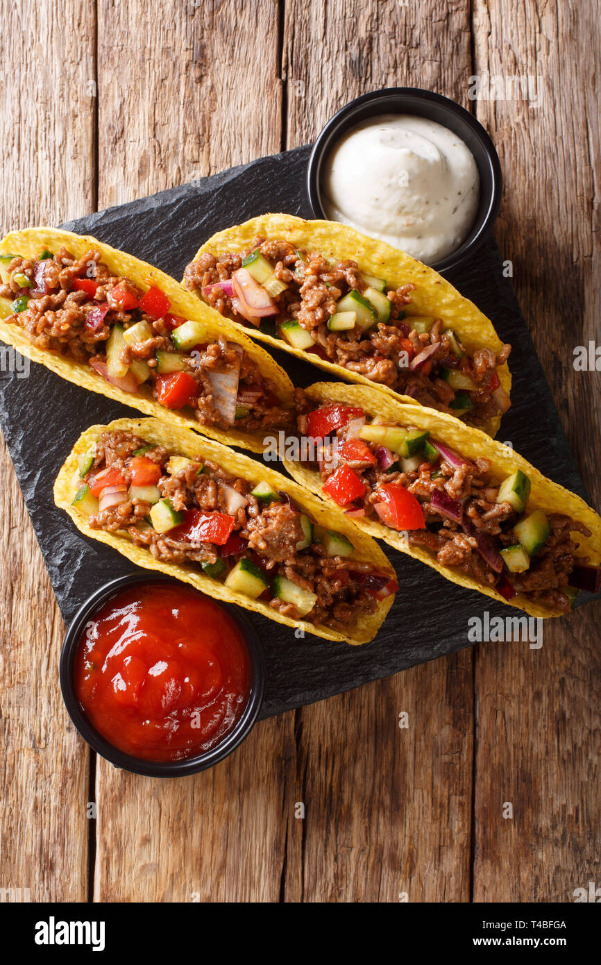 Mexican tacos stuffed with minced beef and vegetables close-up on the table. Vertical top view from above Stock Photo
