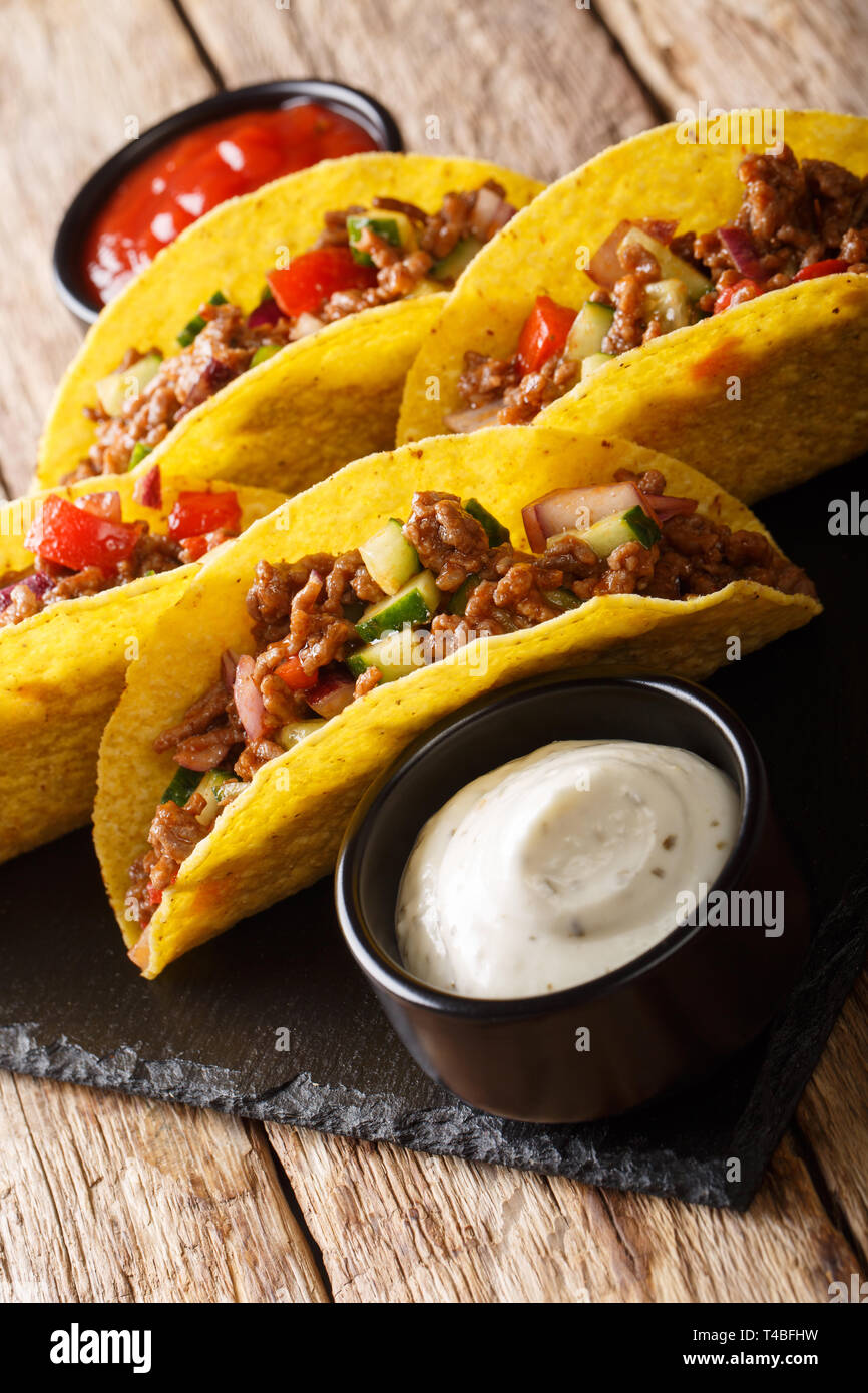 Mexican tacos stuffed with minced beef and vegetables close-up on the table. vertical Stock Photo