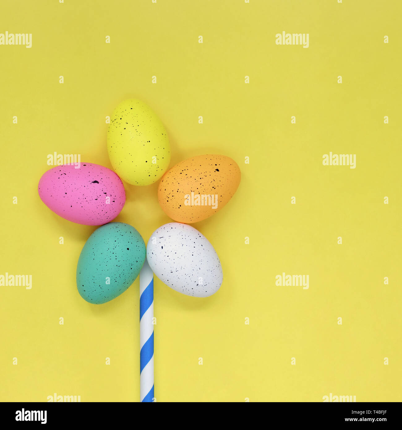 Flower made of colourful Easter eggs, against a yellow background Stock Photo