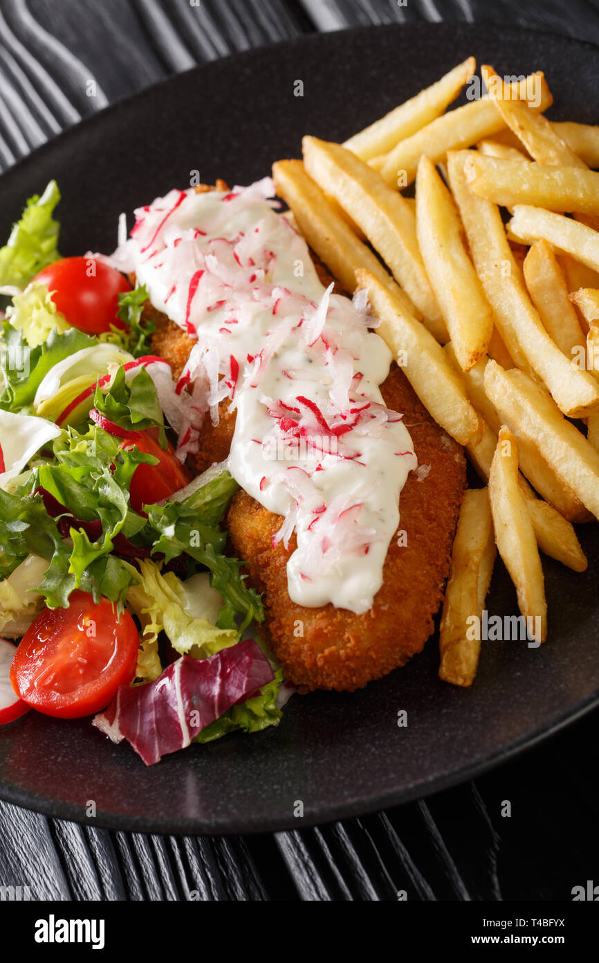 pollock in breadcrumbs garnished with French fries and fresh salad closeup on a plate. vertical Stock Photo