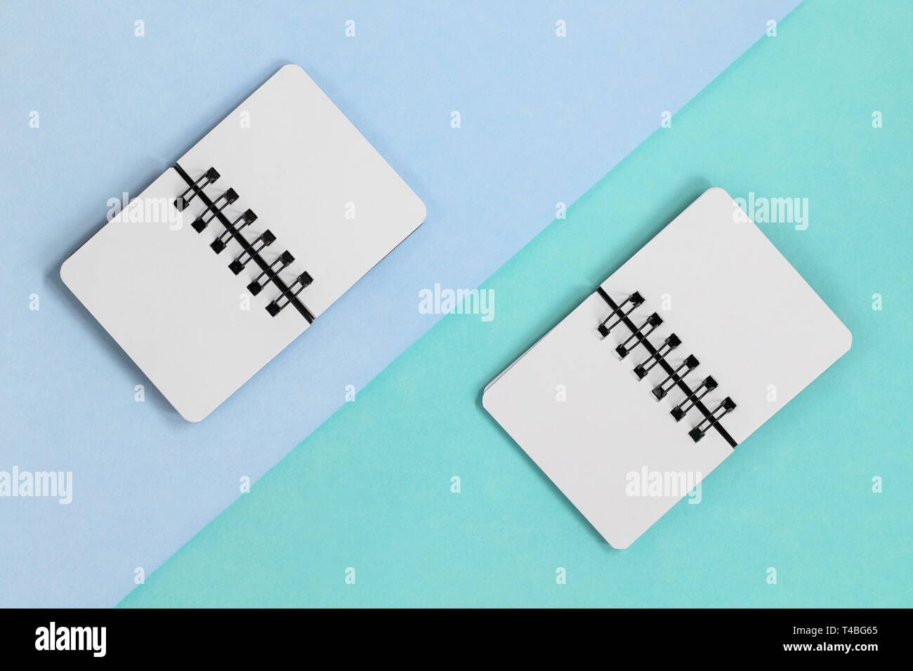 Two open paper spiral notebooks on a diagonal colored backround. Top flat lay view with blue green colors Stock Photo