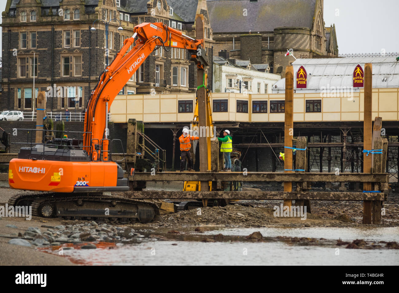 Contractors from Afan Engineering at work  at low tide repairing and renovating the heavily worm-damaged wooden jetty pier on Aberystwyth north beach. Wales UK. March 23 2019 Stock Photo