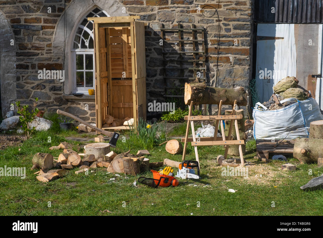 Sustainable energy in the UK: Softwood logs outside a cottage in west wales, ready to be chopped up for firewood for a wood burning stove. Stock Photo