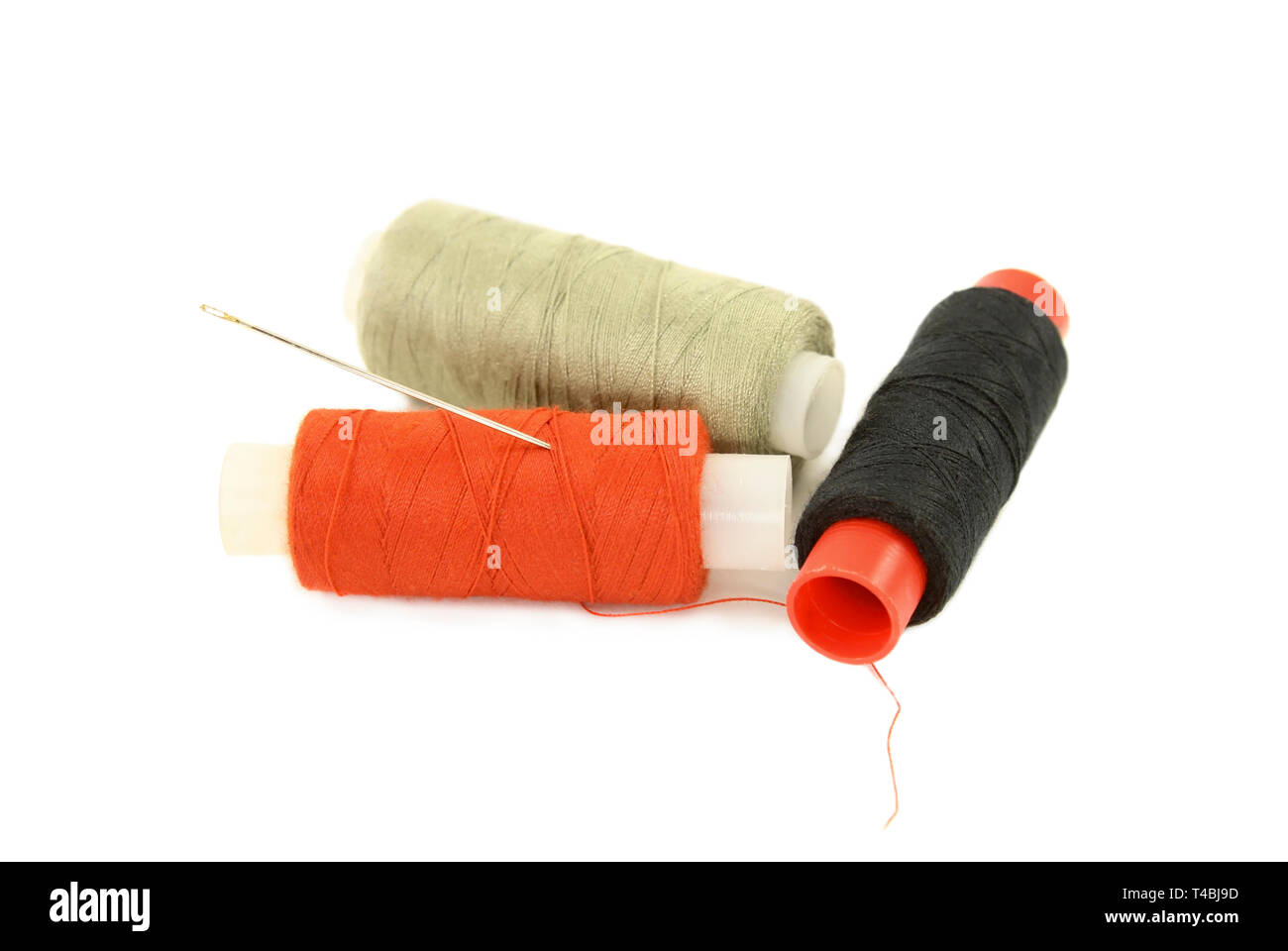 Spools with multi-colored sewing thread and needle isolated on white Stock Photo