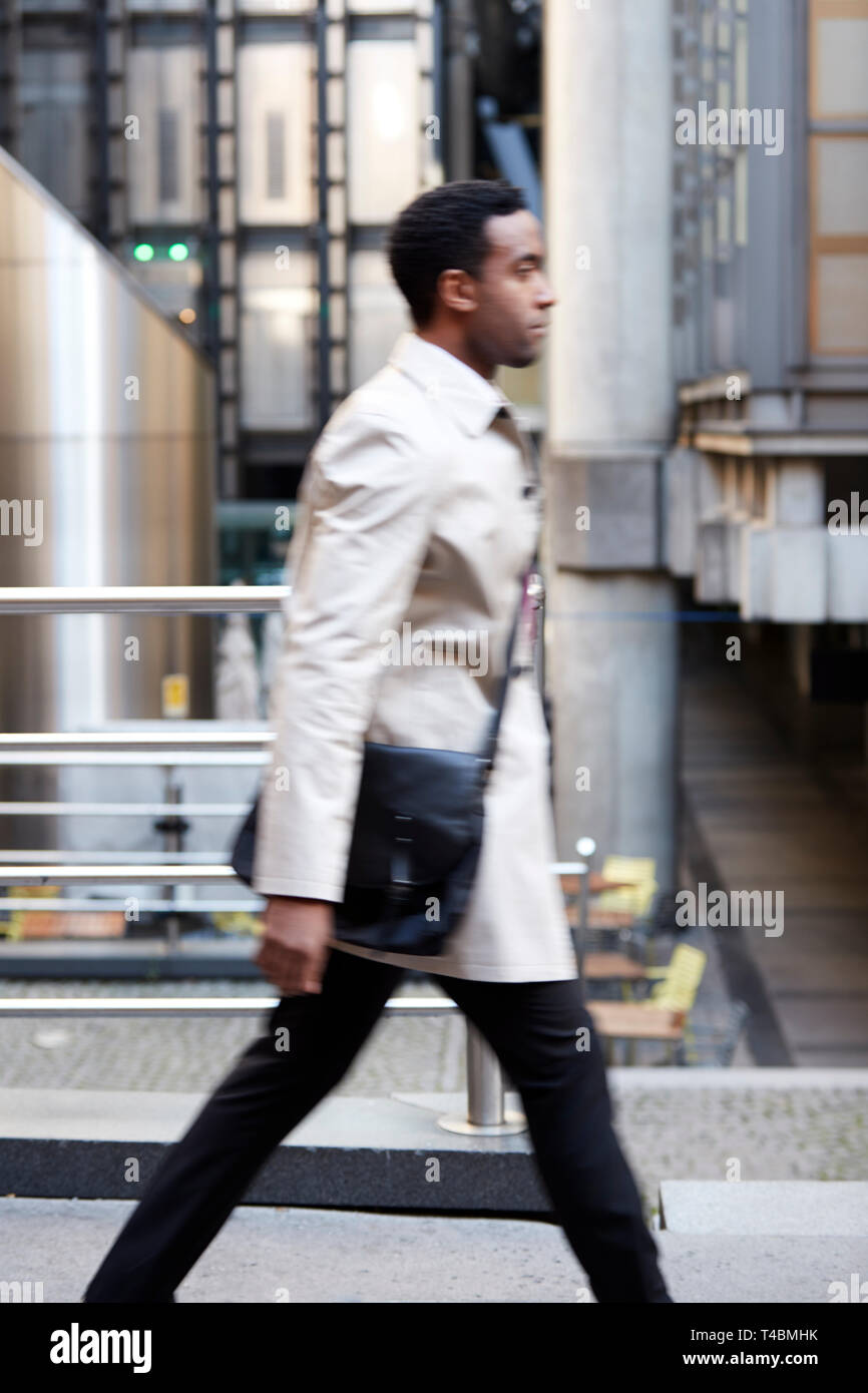 Side view of a young black businessman walking in a street in the city ...