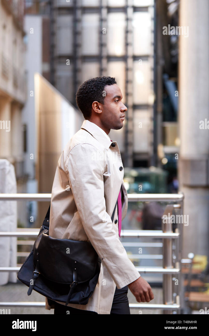 Side view of a young black businessman walking in a street in the city ...