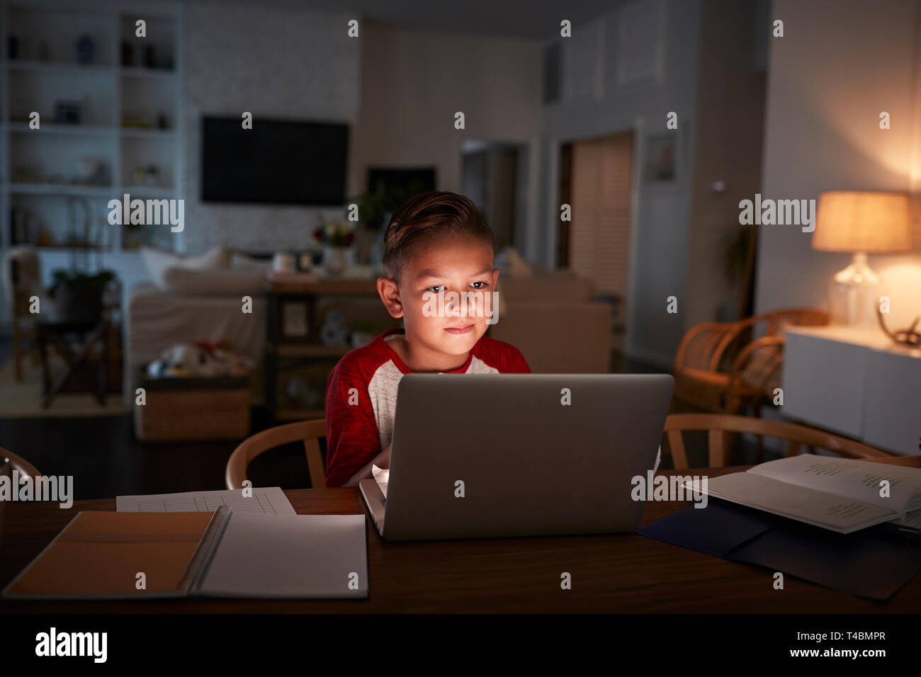Pre-teen Hispanic boy sitting at dining table doing his homework using a laptop computer, front view Stock Photo