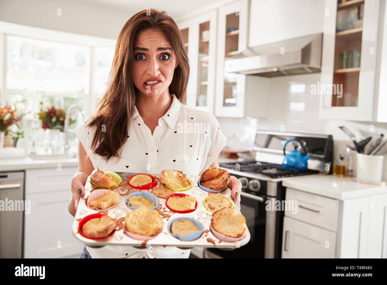 Millennial Hispanic woman presenting her cakes to camera after a baking disaster, close up Stock Photo