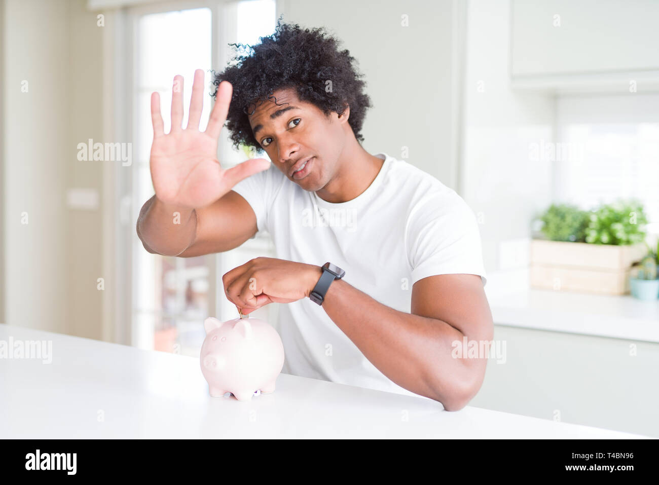 African American man putting a coin inside piggy bank with open hand ...