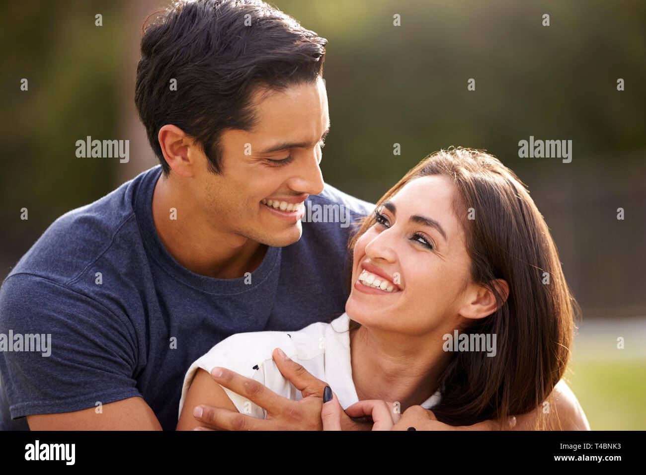 Young Hispanic couple looking at each other smiling, close up Stock ...