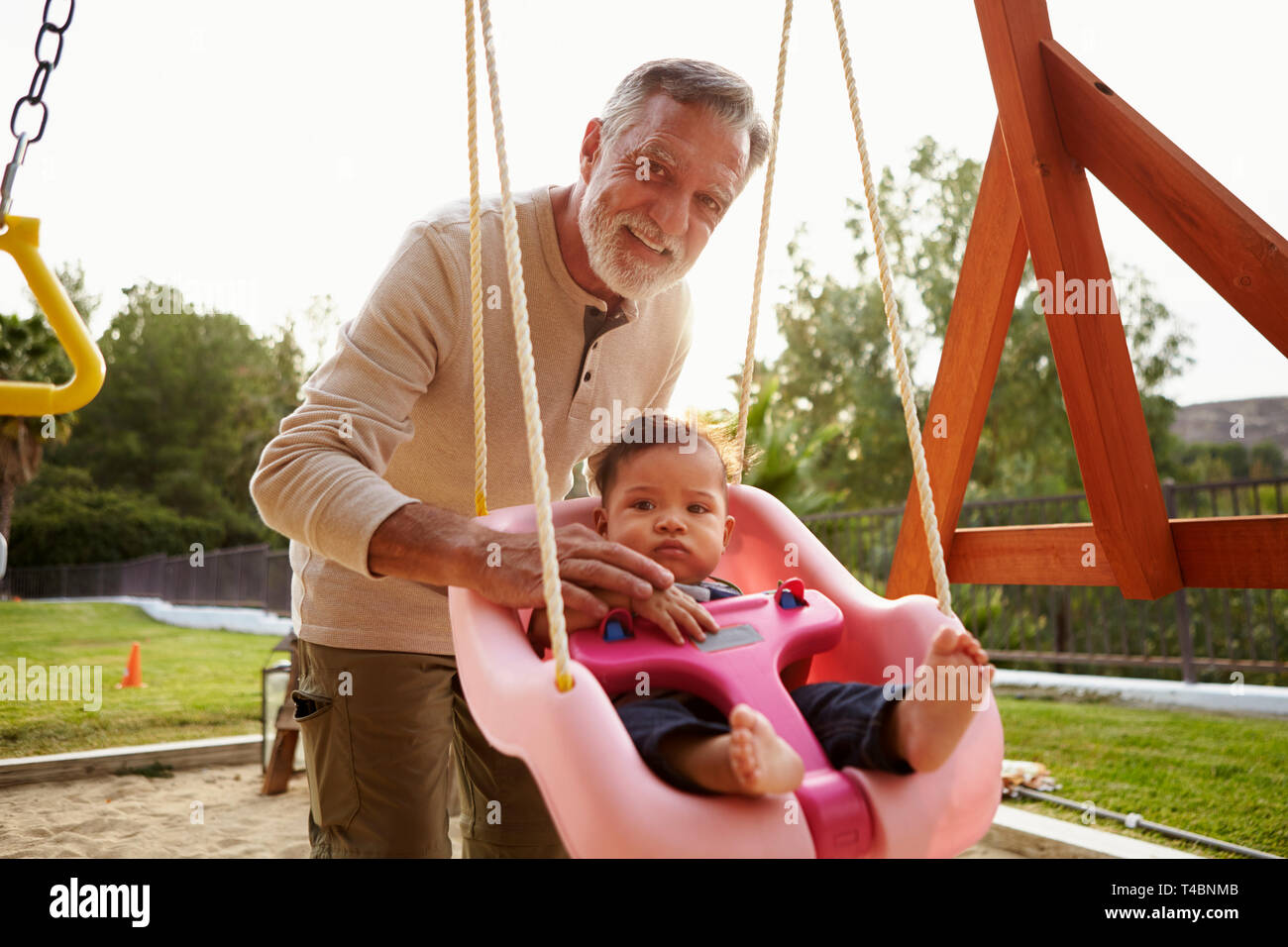 Senior Hispanic Grandfather Pushing His Baby Grandson On A