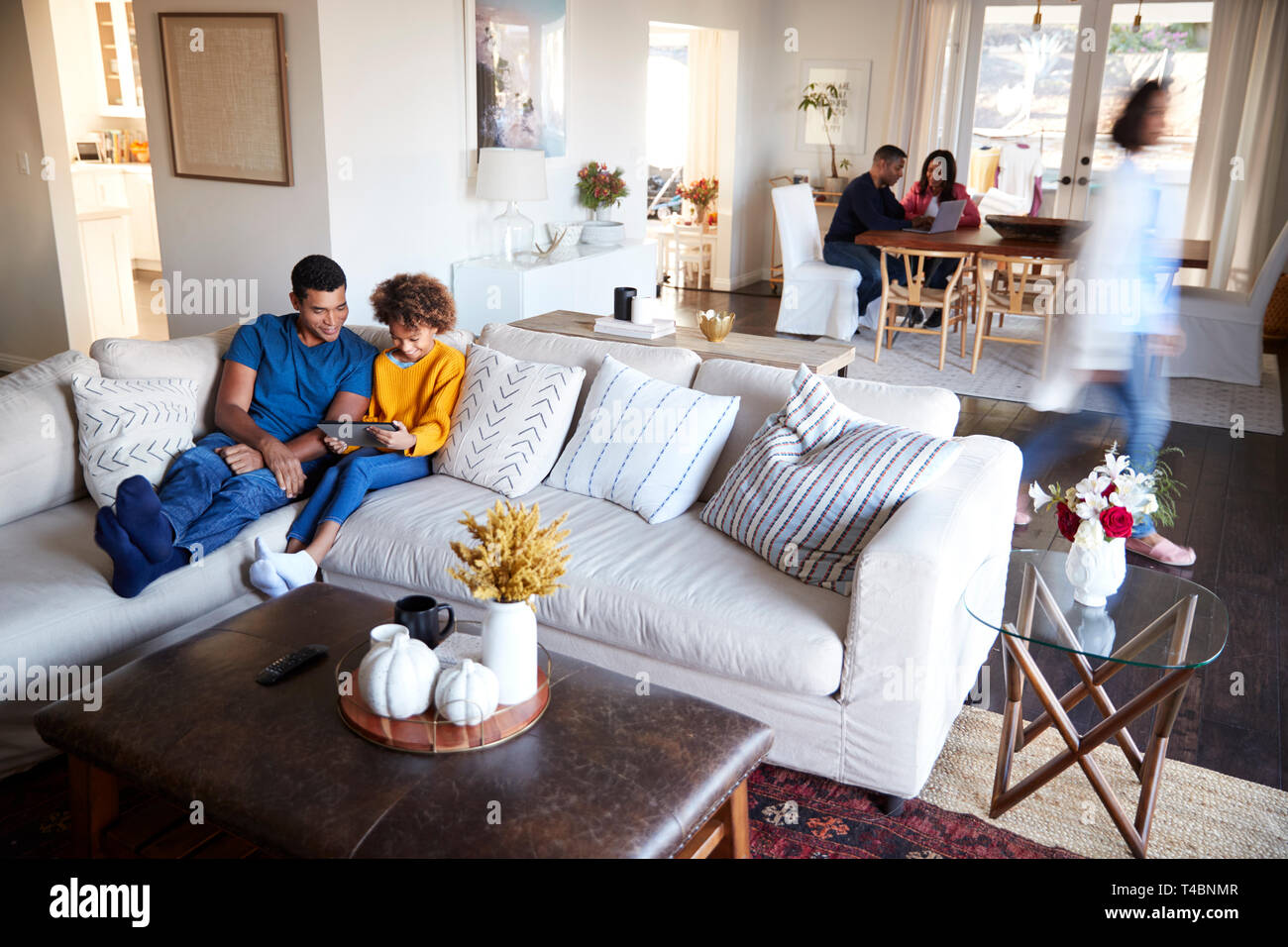 Three generation family family spending time in their open plan living room and kitchen diner, father and daughter in the foreground, elevated view, motion blur Stock Photo