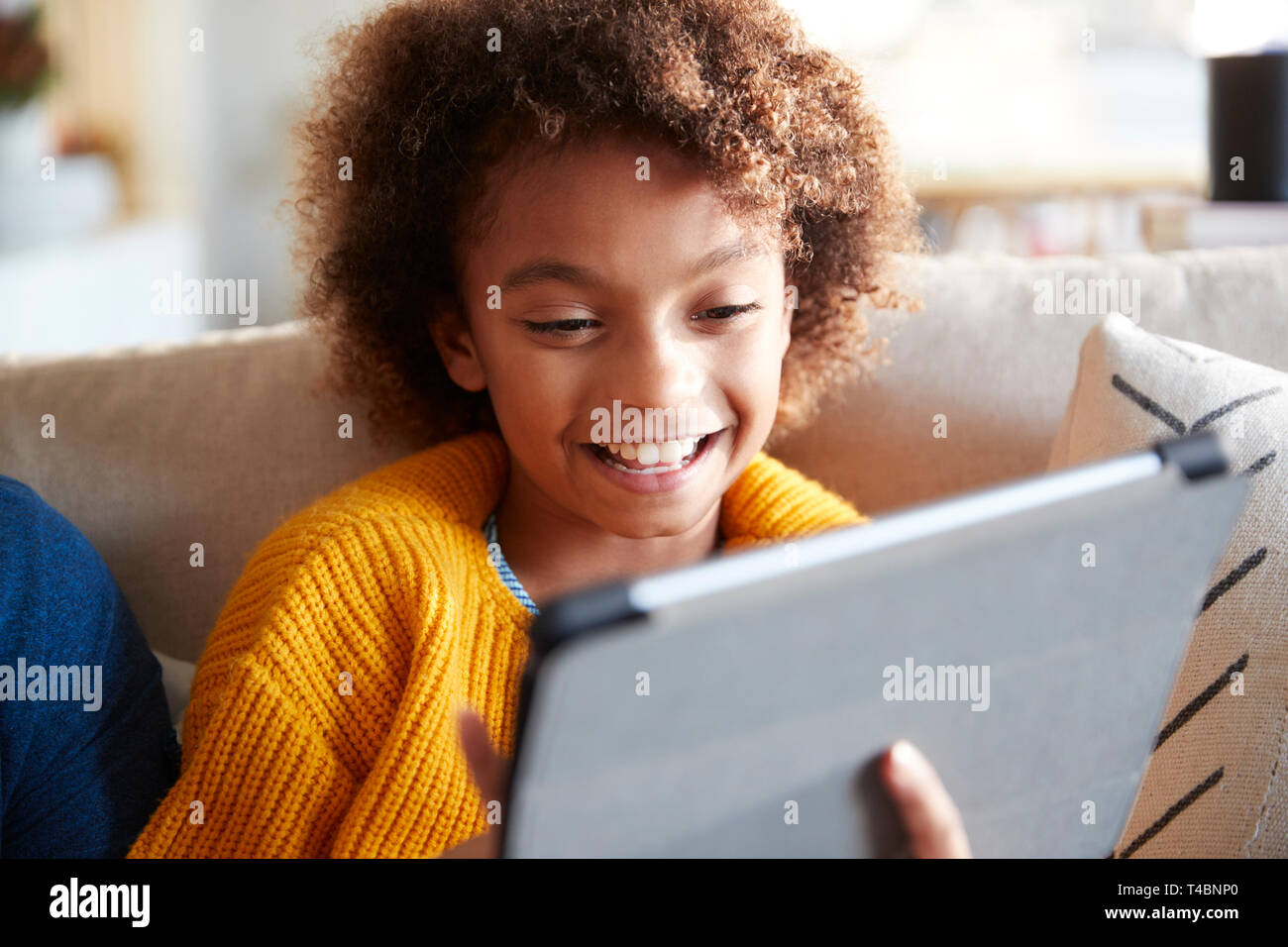 Portrait of pre-teen girl looking at tablet computer screen laughing, close up, selective focus Stock Photo