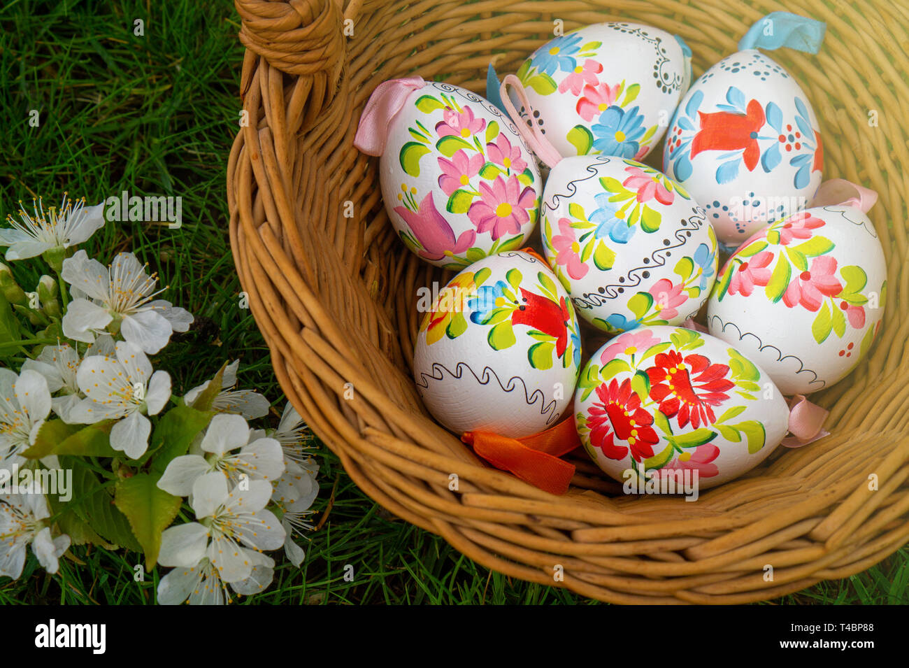 Close up of colorful decorted hand painted Easter eggs in a basket on grass with cherry bossom Stock Photo