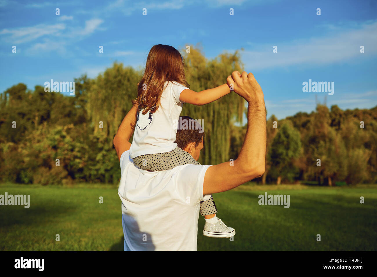 Father playing and carrying his daughter on shoulders. Stock Photo