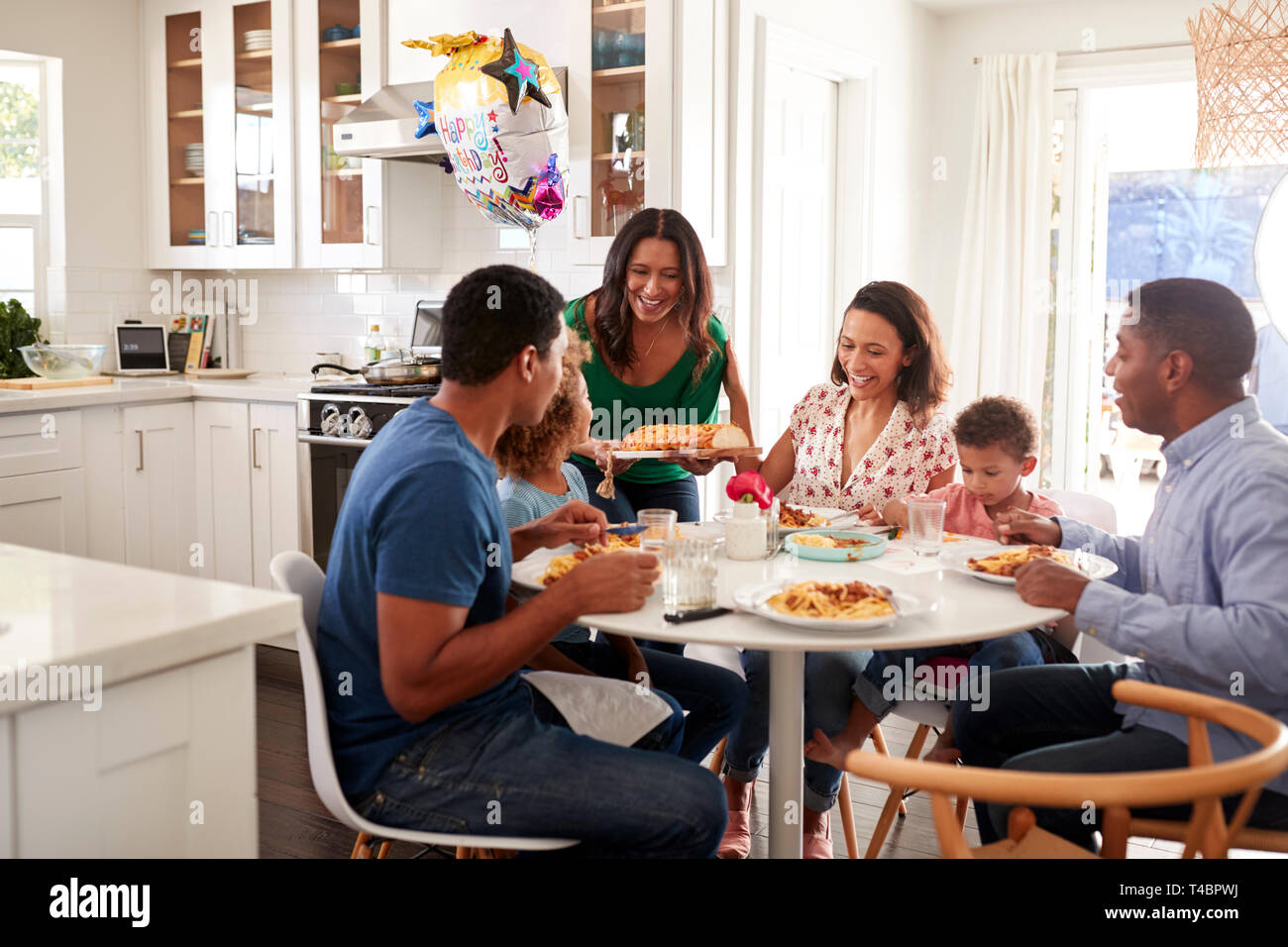 Mixed race three generation family sitting together at the kitchen ...