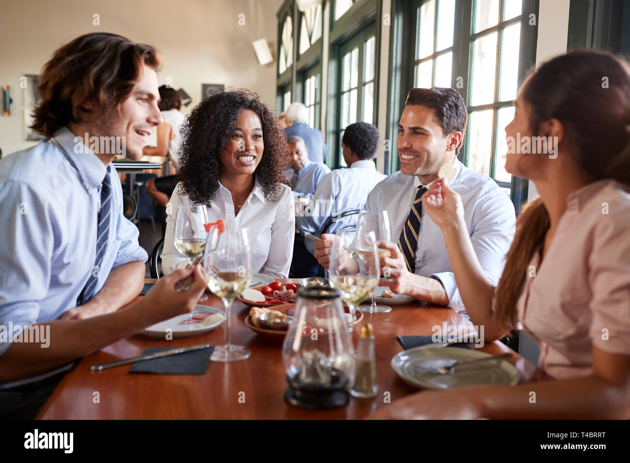 Business Colleagues Sitting Around Restaurant Table Enjoying Meal Together Stock Photo