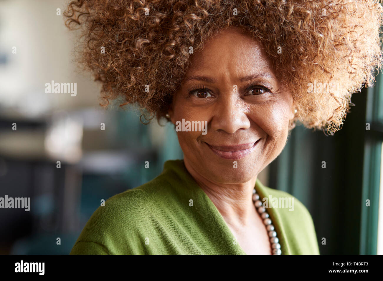 Portrait Of Smiling Senior Woman Sitting In Restaurant Stock Photo