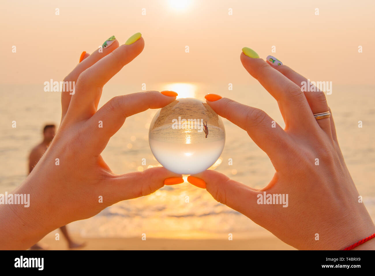 Lens ball in hand with reflection of sea and sunset on the beach Stock ...