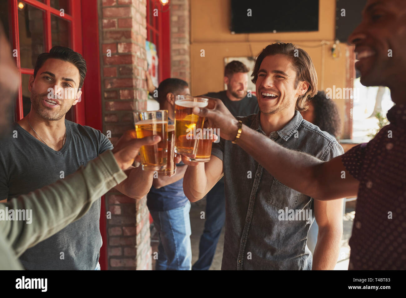 Group Of Male Friends Meeting In Sports Bar Making Toast Together Stock Photo