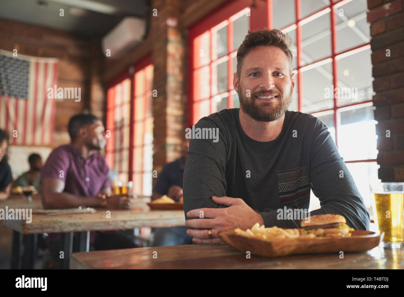 Portrait Of Man In Sports Bar Eating Burger And Fries Stock Photo