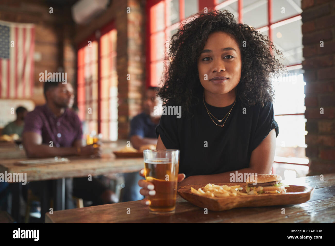 Portrait Of Woman In Sports Bar Eating Burger And Fries Stock Photo