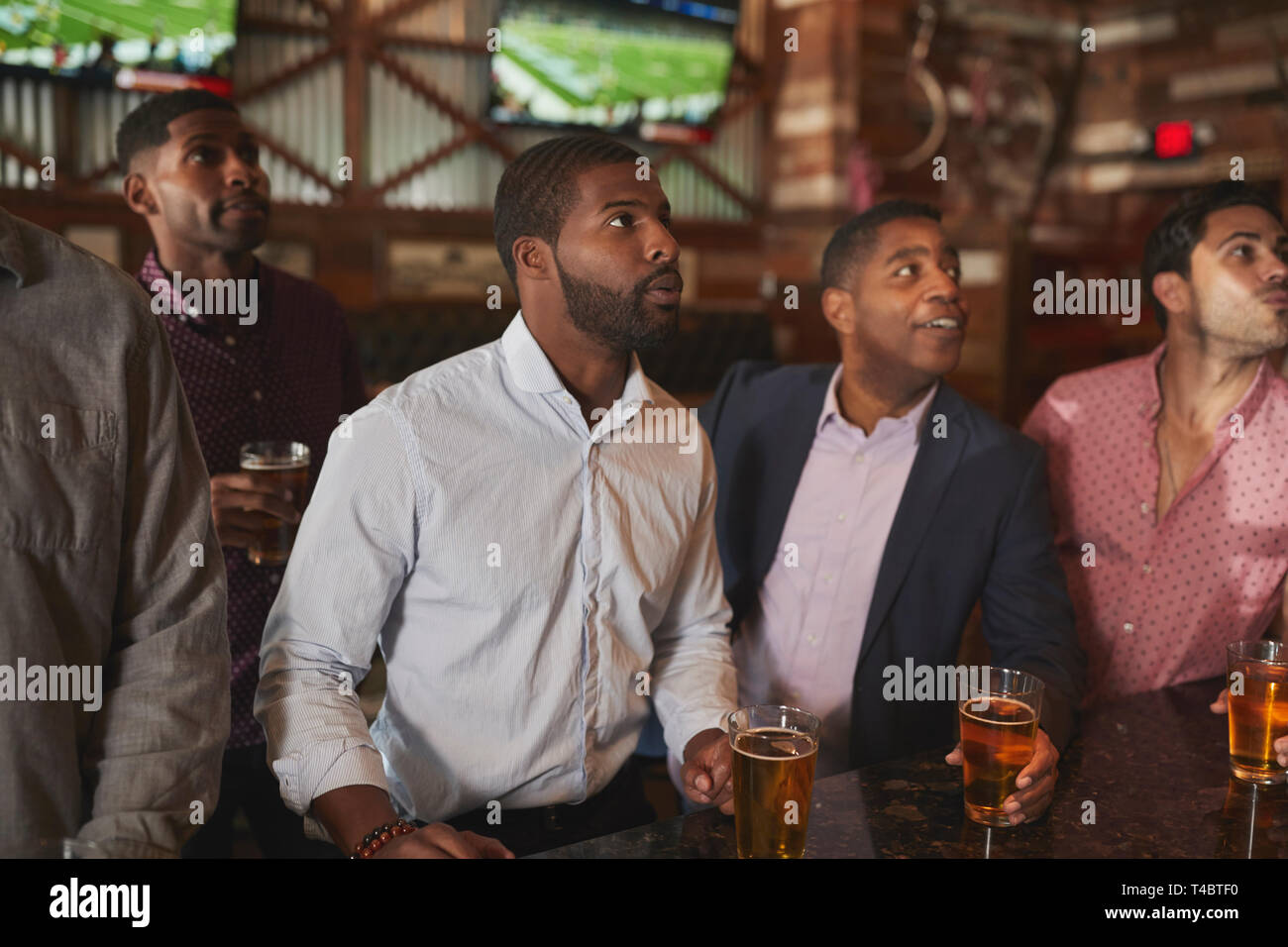 Group Of Male Friends On Night Out For Bachelor Party Watching Screens Stock Photo