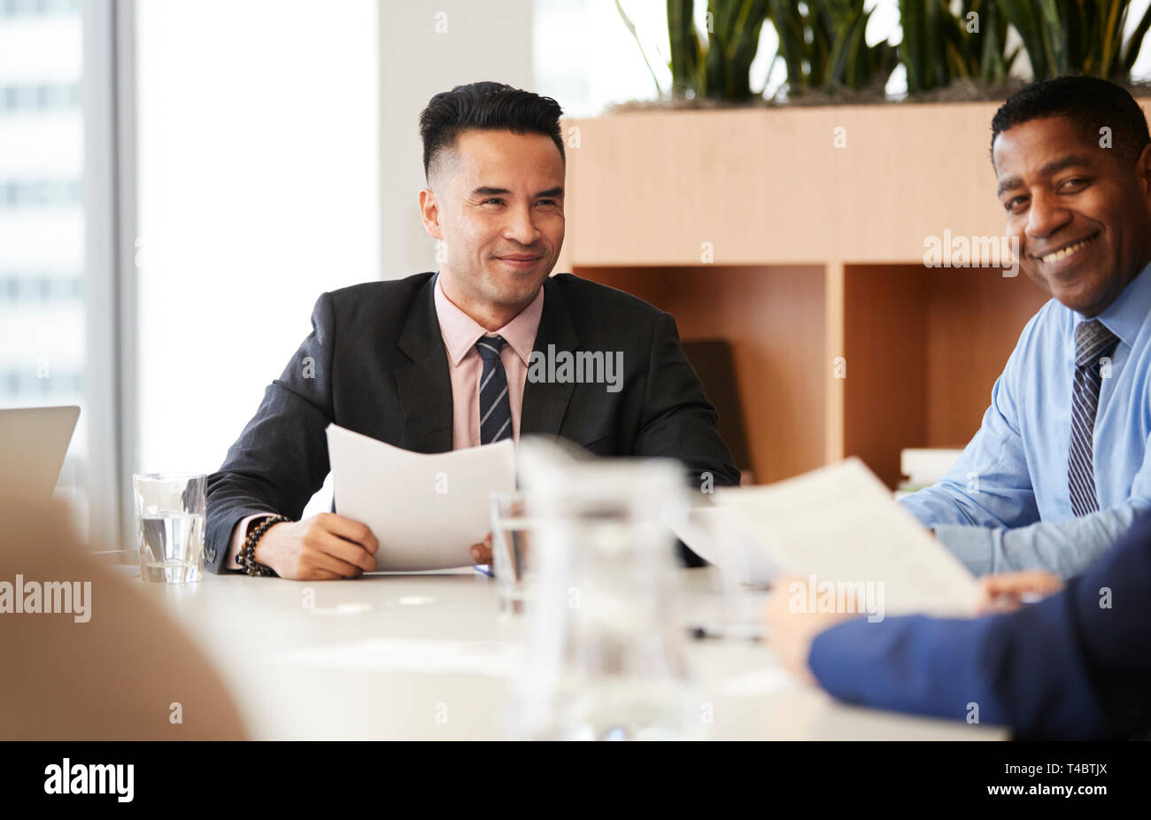 Businessman With Paperwork Sitting At Table Meeting With Colleagues In Modern Office Stock Photo