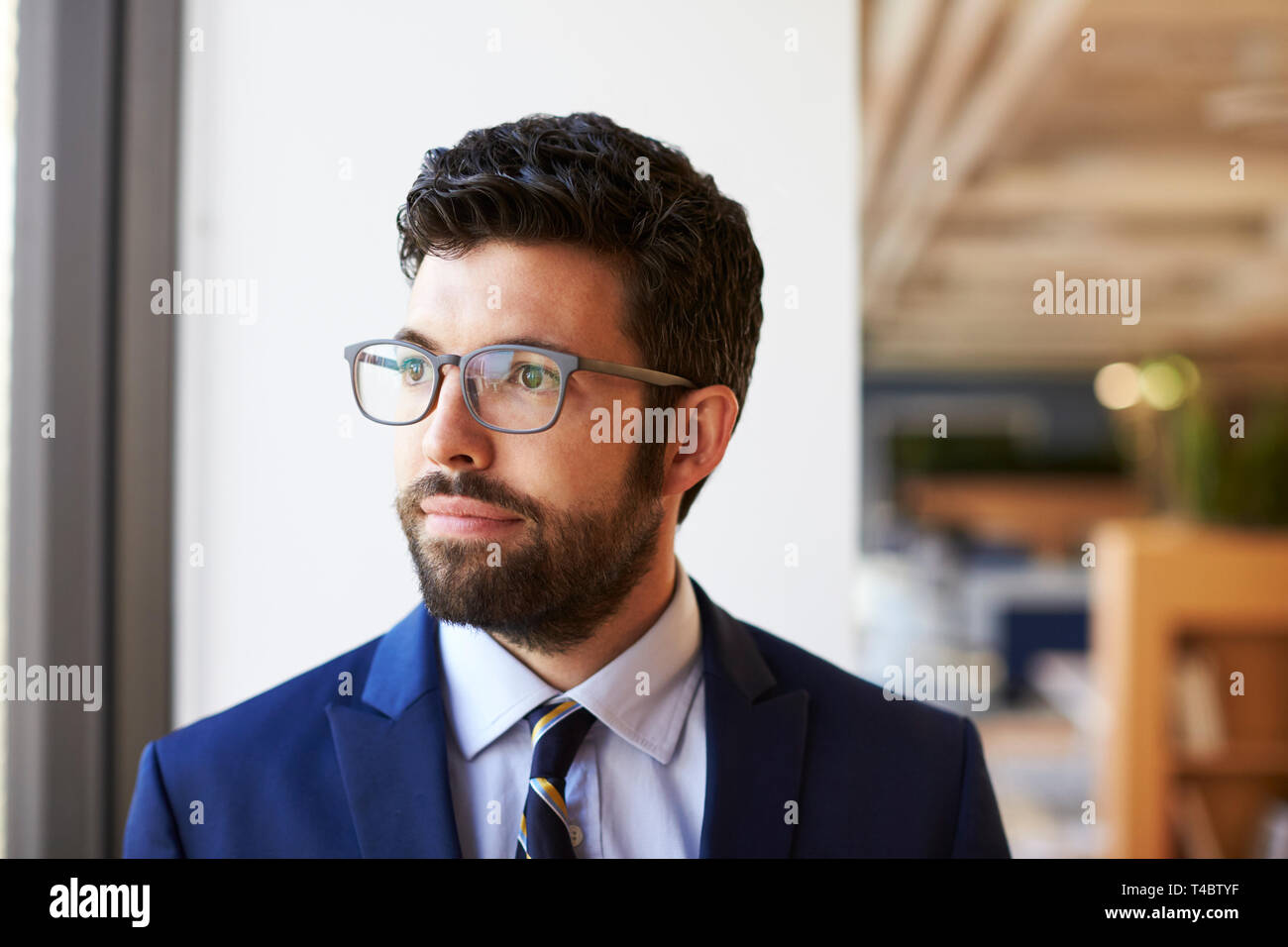 Businessman In Modern Office Standing By Window Stock Photo