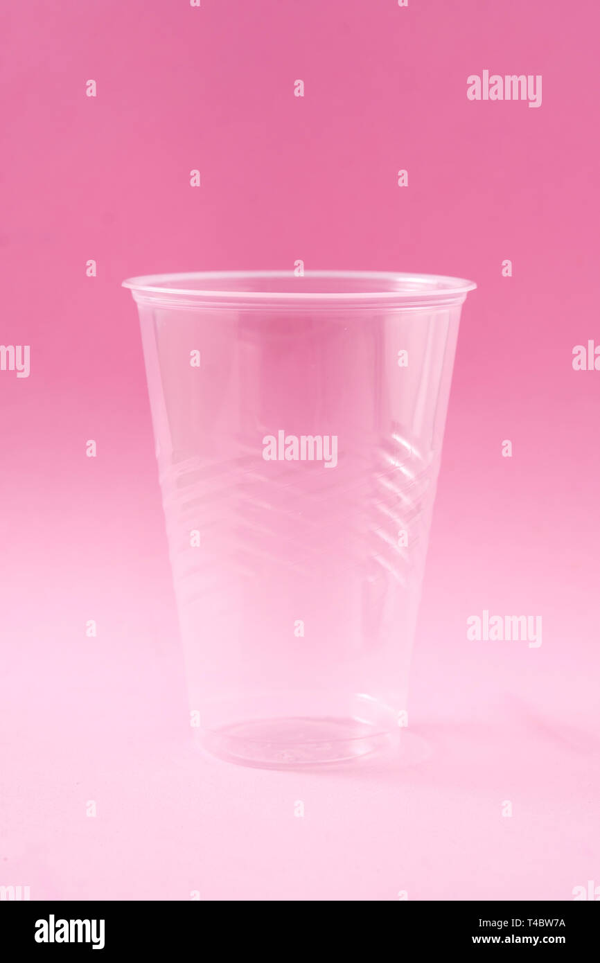 Disposable waste plastic glass on pink background. Stock Photo